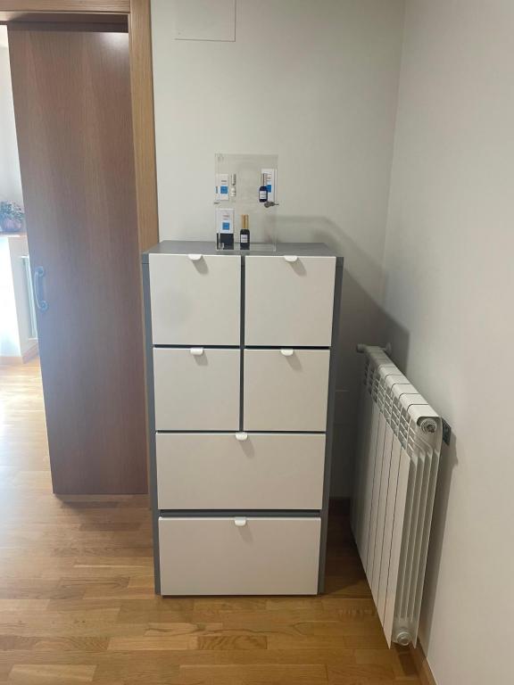 Una cómoda blanca en una habitación con un radiador. en El Rincón del Ángel, en Jaca