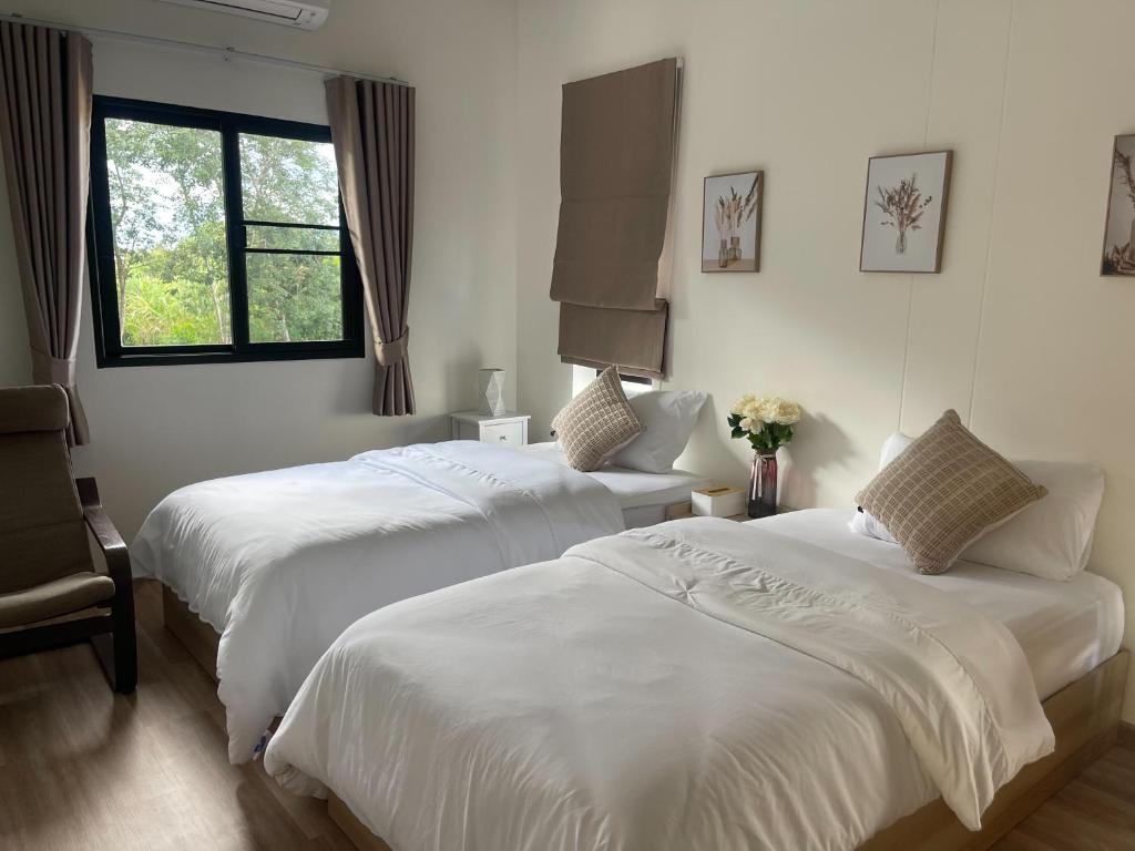 two beds in a room with white sheets and a window at Sleep Shot Pool Villa in Ban Fang Min