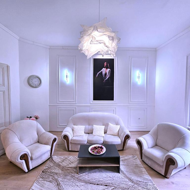 a living room with white furniture and a chandelier at Heroina in Stepanovićevo