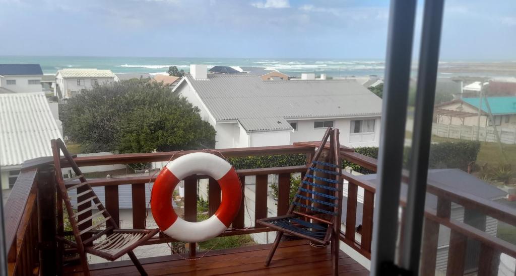 a balcony with two chairs and a life preserver at 5 Cliff Street in Agulhas