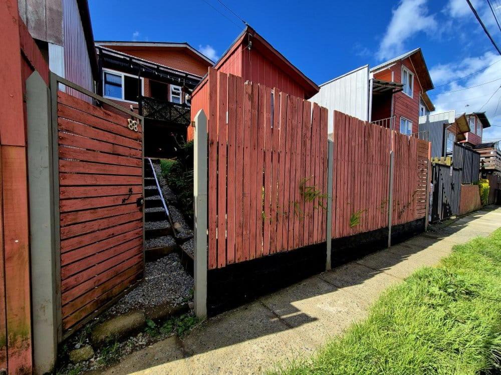a red fence next to a red house at Cabañas Tupananchiskama in Ancud