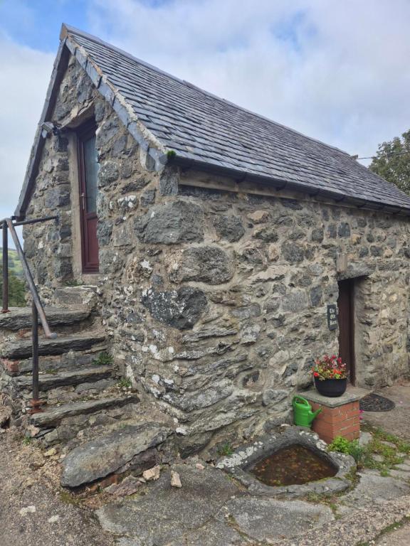 a stone house with a stone staircase and a window at The Old Barn in Bettws Gwerfil Goch