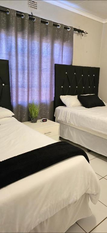 two beds in a room with a purple curtain at Vaal Home near Aquadome in Vanderbijlpark
