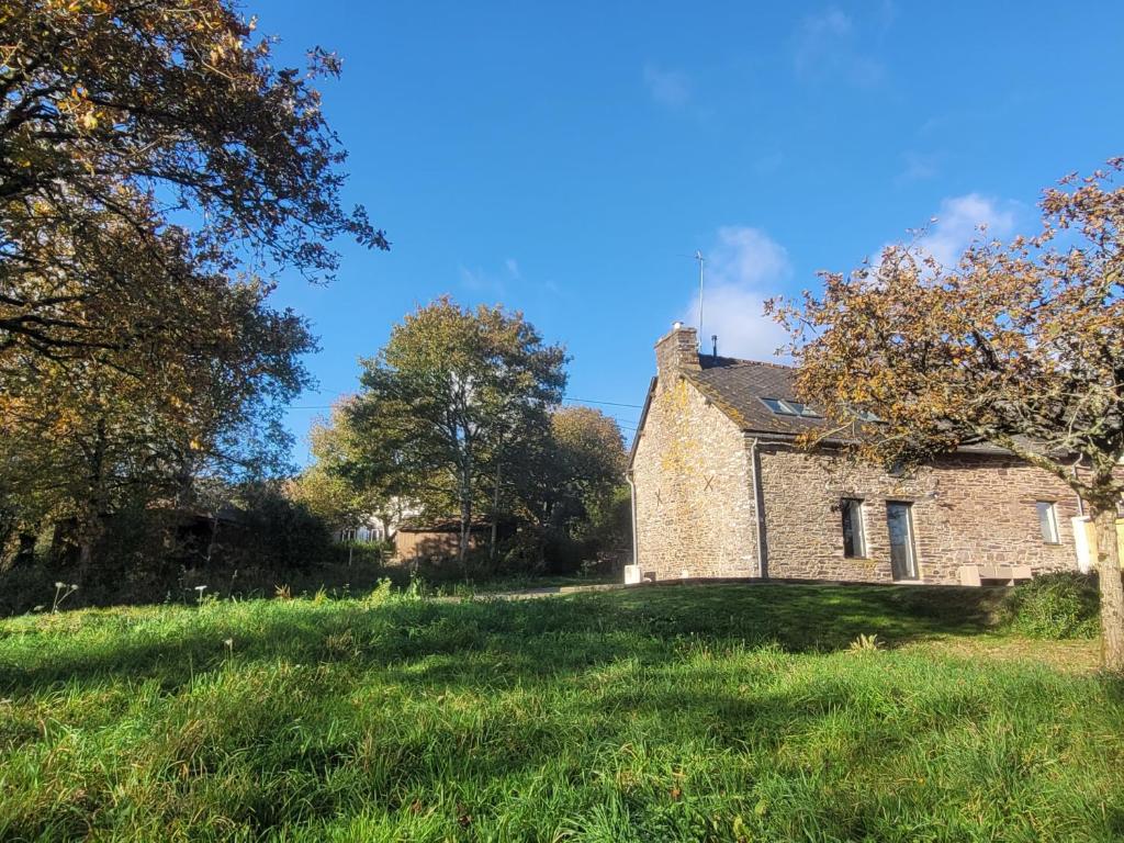 an old stone house on a grassy field at La Maison en Brocéliande in Paimpont