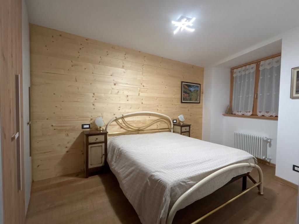 a bedroom with a bed and a wooden wall at Al Mulino in Schilpario