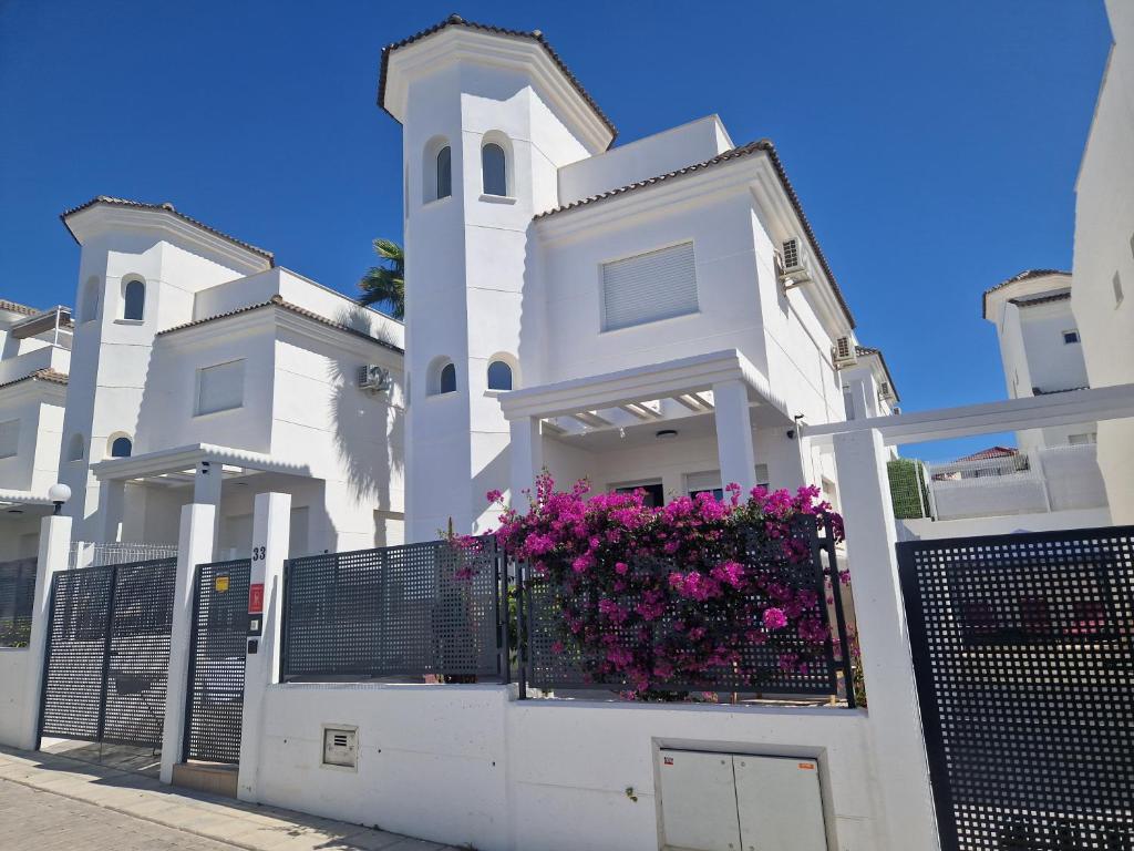 a white building with a balcony with purple flowers at Casa de la Suerte in San Fulgencio