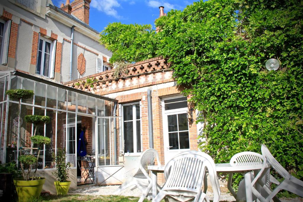 2 chaises blanches et une table devant un bâtiment dans l'établissement les Thiausères, à Romorantin-Lanthenay