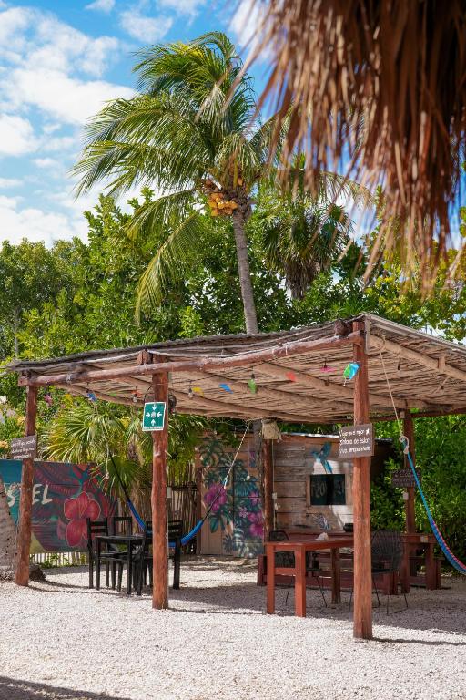 a wooden pavilion with a table and a palm tree at Mapache Hostel in Holbox Island