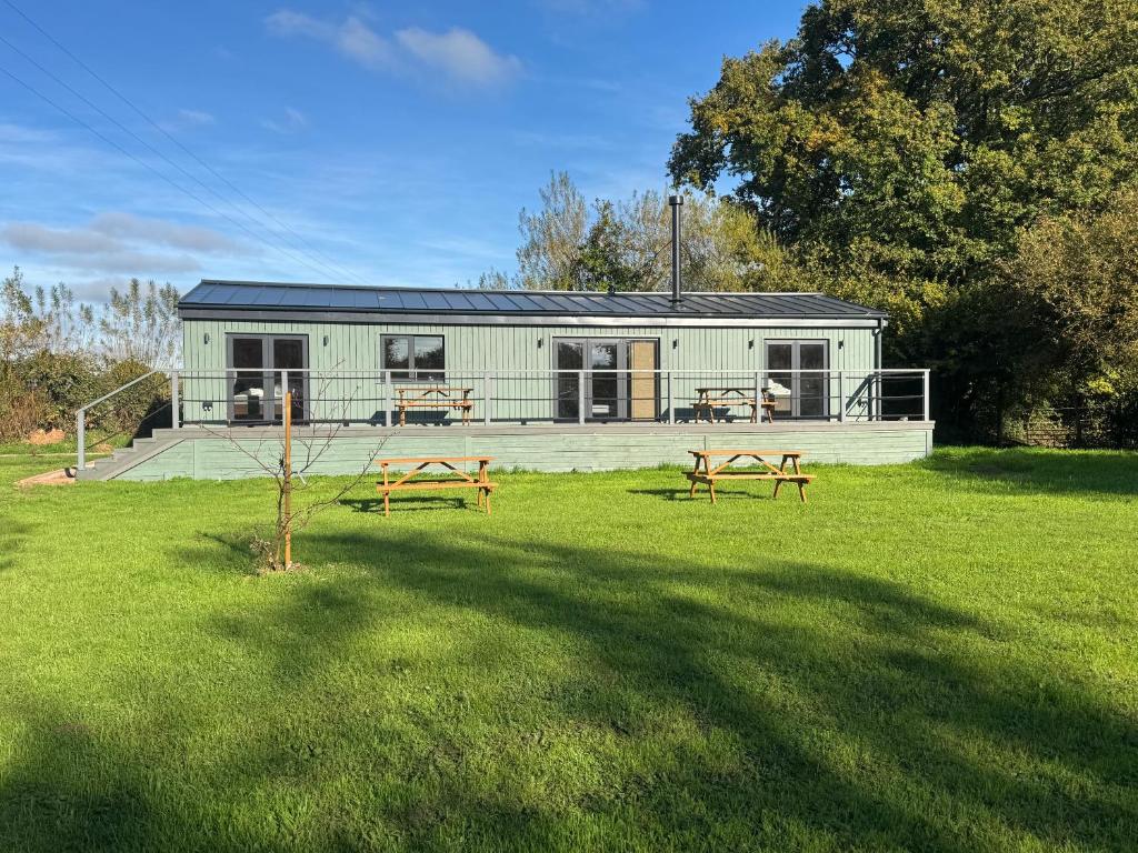 ein Gewächshaus mit zwei Bänken im Garten in der Unterkunft Lake Lodge at Farthings Farm in Clyst Saint Lawrence