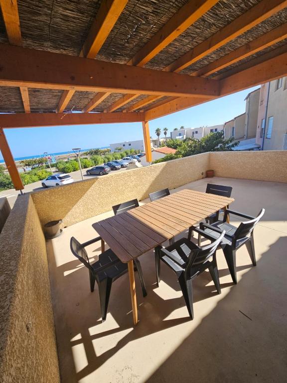 a wooden table and chairs on a patio at La perle rare in Le Barcarès