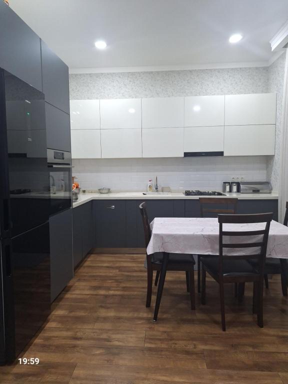 a kitchen with a table and chairs and white cabinets at Tsitadel in Zugdidi