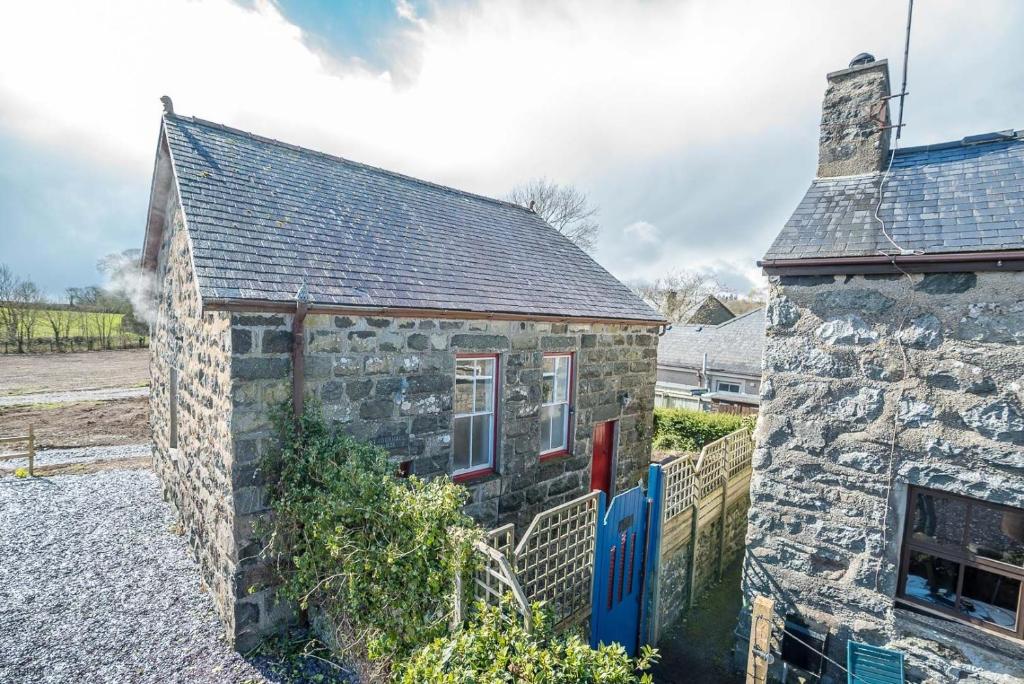 une ancienne maison en pierre avec une porte bleue dans l'établissement Capel-Bach, à Llanystumdwy