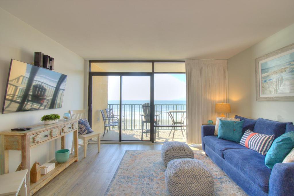 a living room with a blue couch and a balcony at Verandas - 303 in Myrtle Beach
