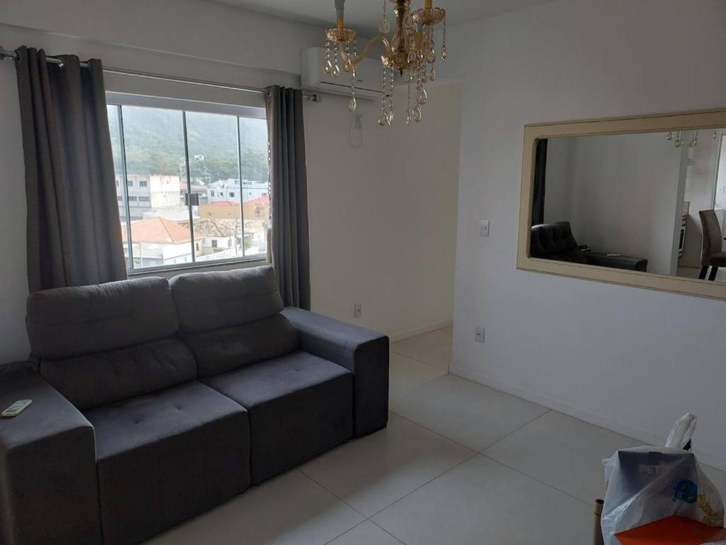 uma sala de estar com um sofá e um espelho grande em Apartamento de 2 quartos equipado em Imbituba sc em Imbituba