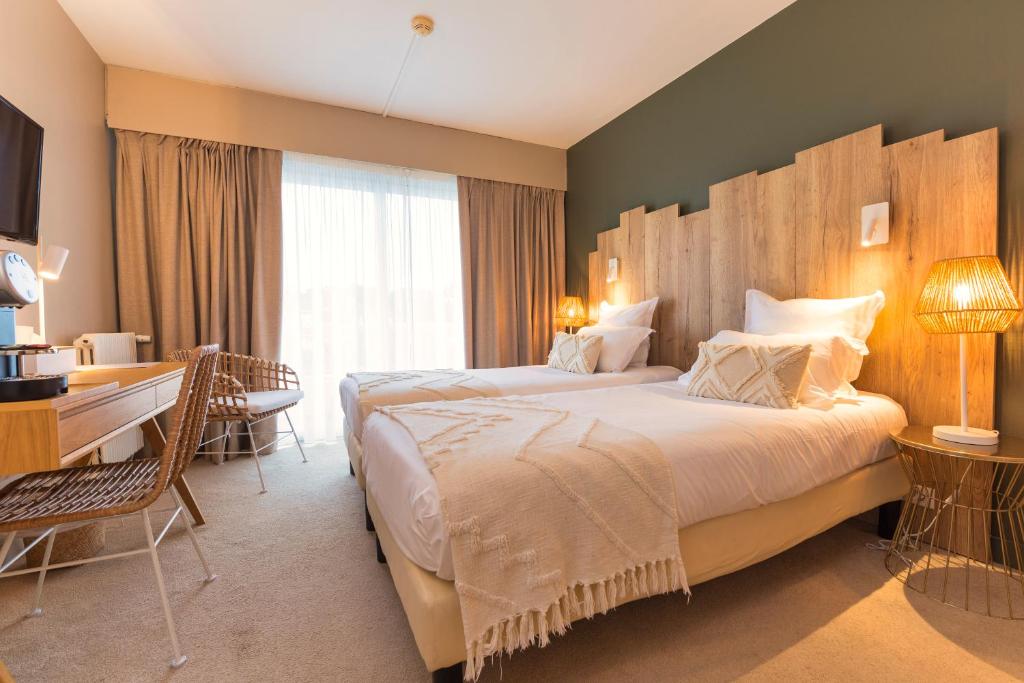 a hotel room with a large bed and a desk at Hôtel BO & MIA in La Baule