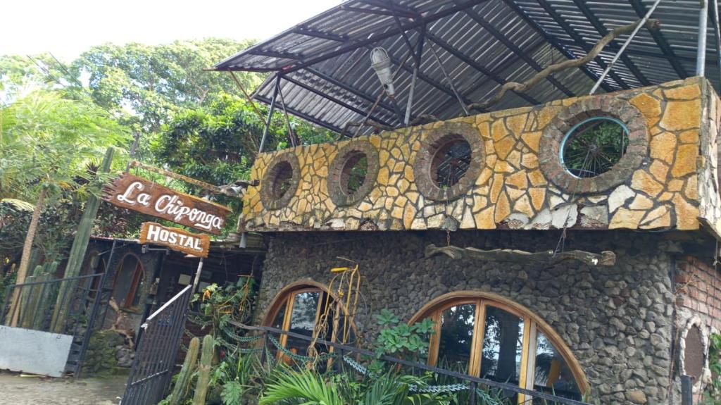 a building with a stone wall with windows and a sign at la chiponga beach hostel in Altagracia