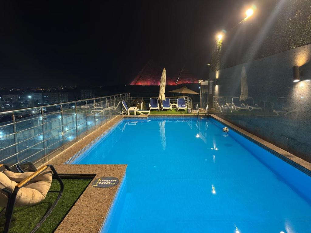 ein großer Pool auf einem Gebäude in der Nacht in der Unterkunft Pyramids Charm Hotel in Kairo