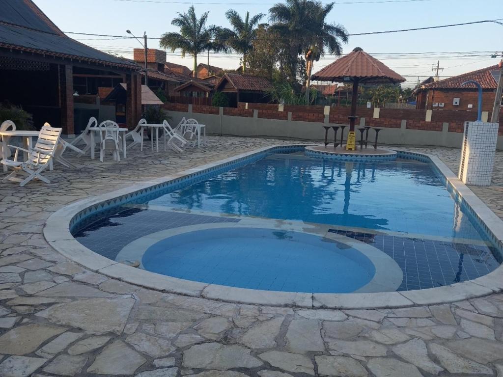 una piscina in un patio con sedie e ombrellone di Chalé rústico e aconchegante em Gravatá a Gravatá