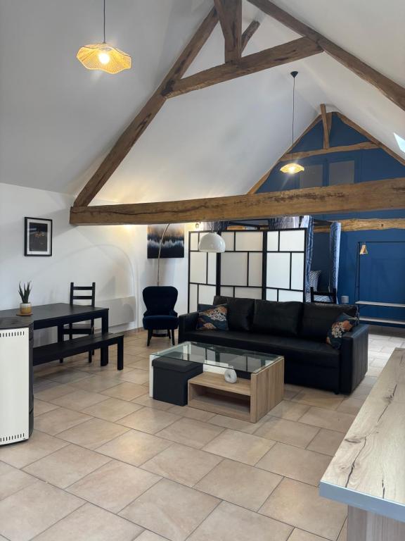 Una sala de estar con un sofá negro y una mesa. en Le Merisier, 