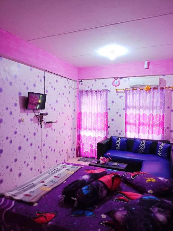 a room with a bed and a couch and pink lights at Penginapan Purple Syariah 
