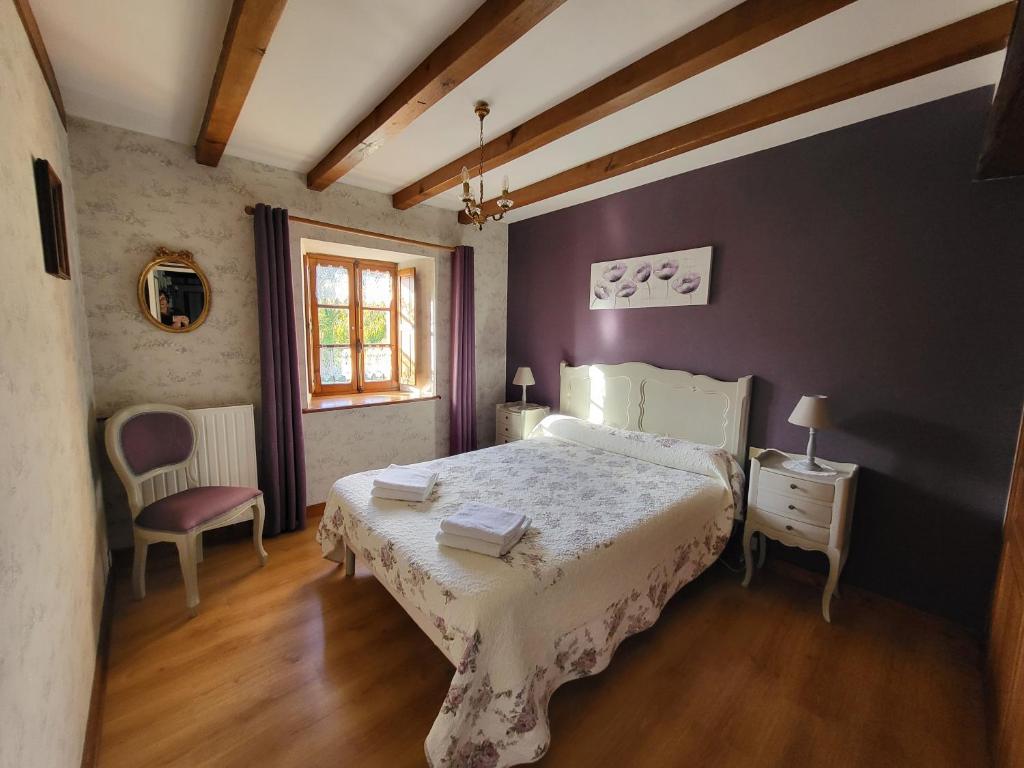 a bedroom with a bed and a chair and a window at Le Logis d'Aliénor - Baie du Mont St-Michel in Baguer-Pican