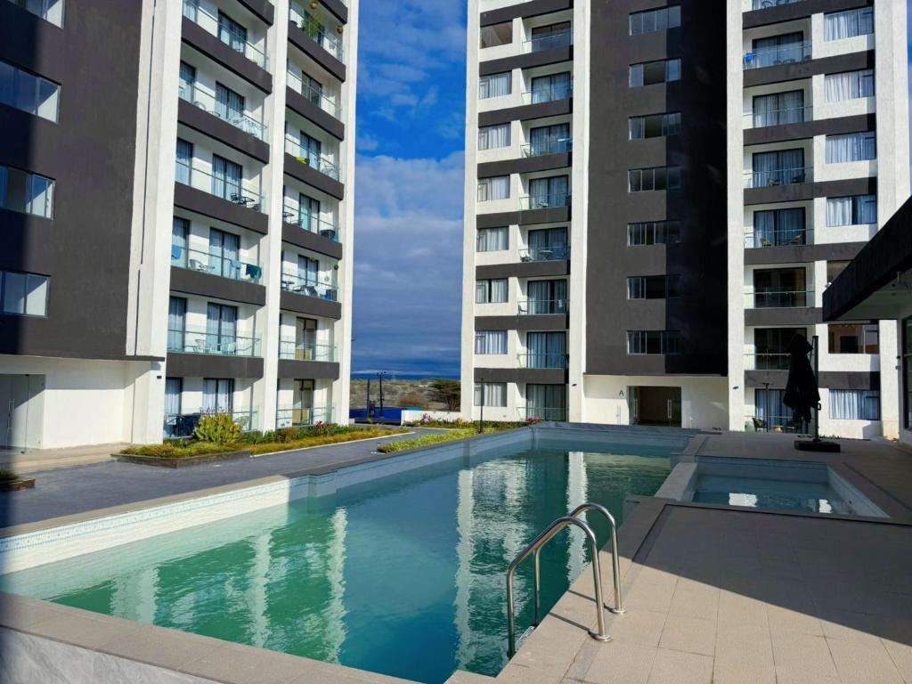 a swimming pool in front of two tall buildings at Artesano one bedroom cozy and comfortable in Syokimau