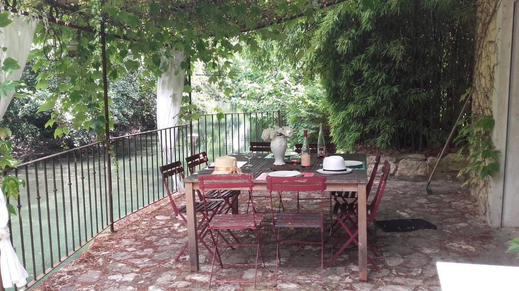 a table and chairs sitting under an arch with a fence at Domaine des Petits Cancets in L'Isle-sur-la-Sorgue