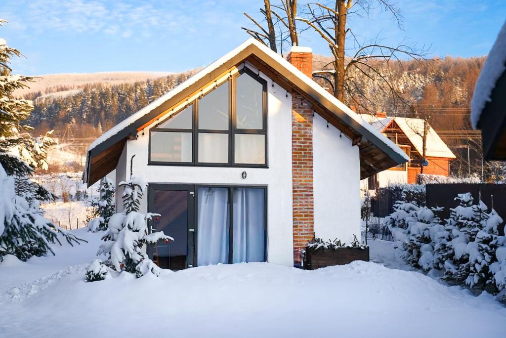 una casa blanca con nieve en el suelo en Nowe Domki Jeleni Szlak, en Ustrzyki Dolne