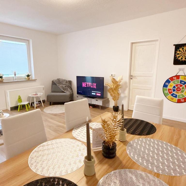 a living room with a table and chairs and a tv at Wohlfühl-Apartment mit großem Balkon, Netflix & Games in Barsinghausen