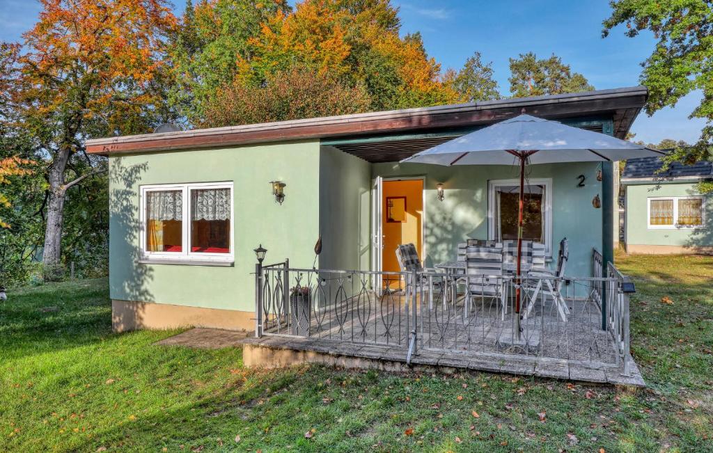 a green house with a deck with chairs and an umbrella at Ferienhaus Boitzenburger Land in Rosenow