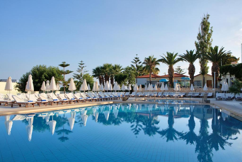 a swimming pool with lounge chairs and umbrellas at Rethymno Mare Royal & Water Park in Skaleta