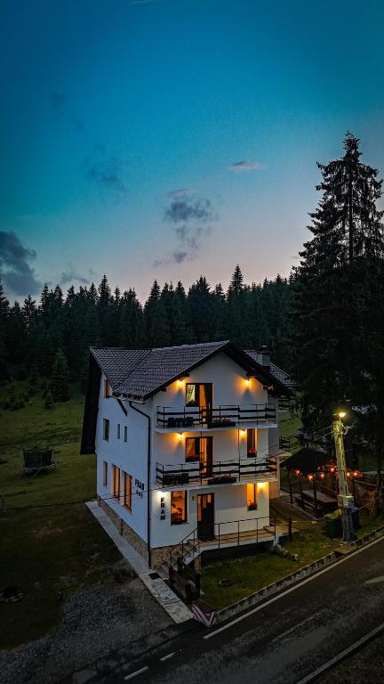 a white house with lights on in a field at CABANA FRAM VÂRTOP in Vartop