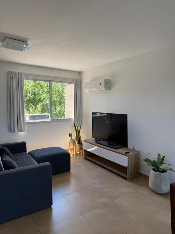 a living room with a couch and a flat screen tv at Departamento Lago Los Molinos in Villa Ciudad de America