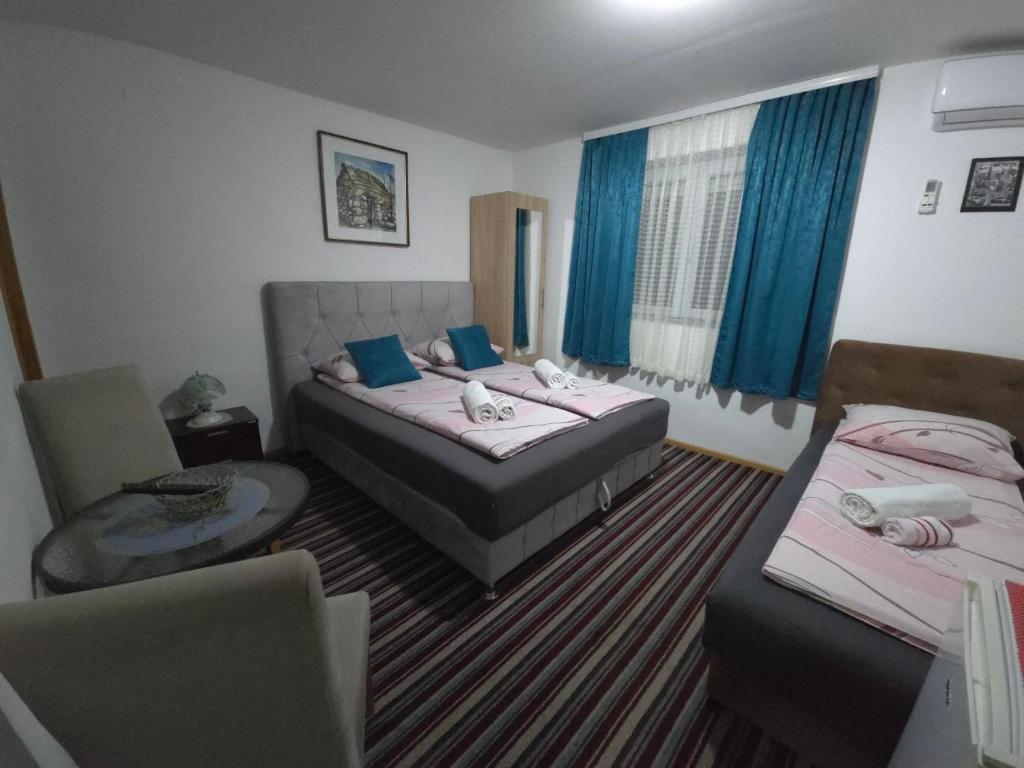 a hotel room with two beds and a chair at Guest House Nana in Mostar