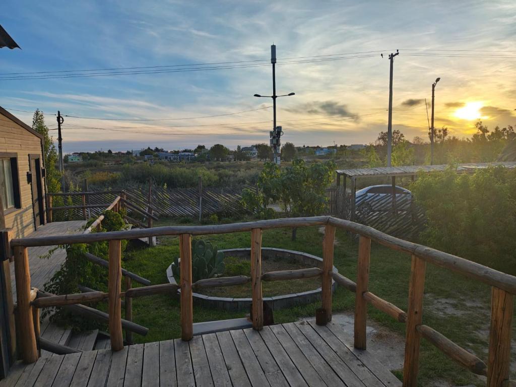 a wooden deck with a railing and a sunset at Las Cabañas in Las Grutas