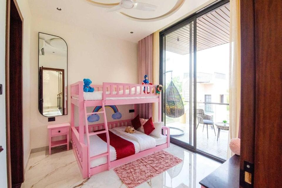 uma beliche rosa em um quarto com um espelho em Villa Papillon by DanCenter | Pvt Pool | Jacuzzi | Kids Room | Udaipur em Thūr