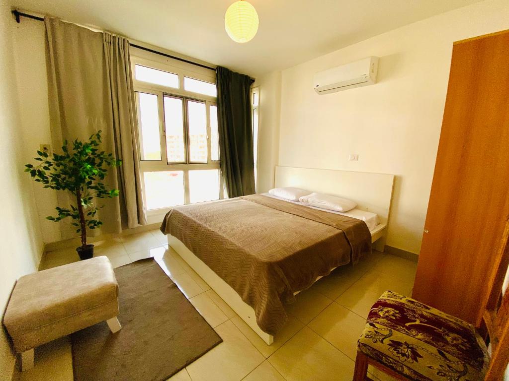 a bedroom with a bed and a large window at A Home to Sleep Wi-Fi AC in Madinaty