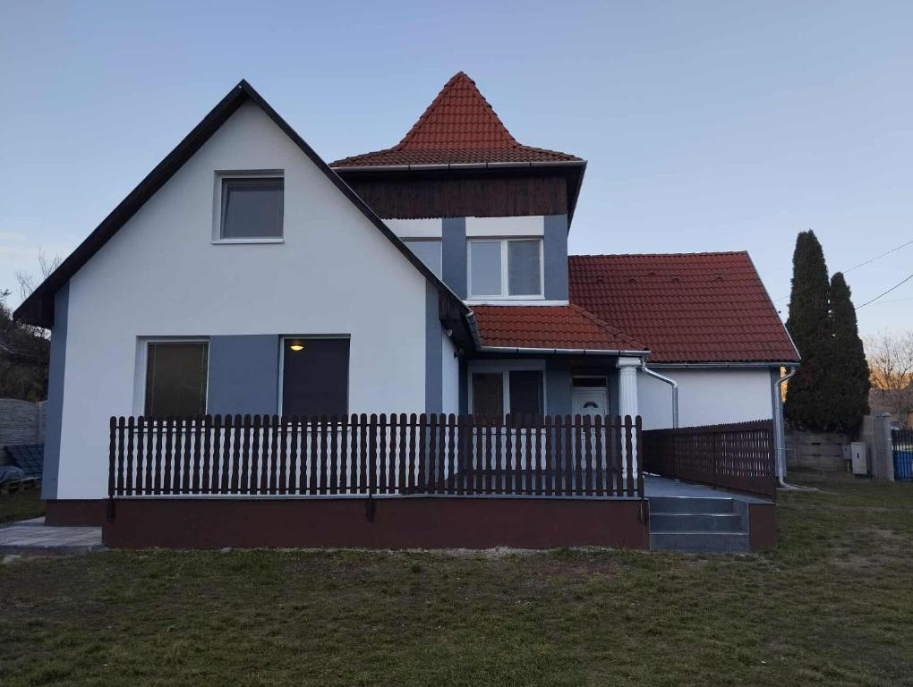 a white house with a fence in a yard at NADENKA & MGR Vendégház in Alsótelekes