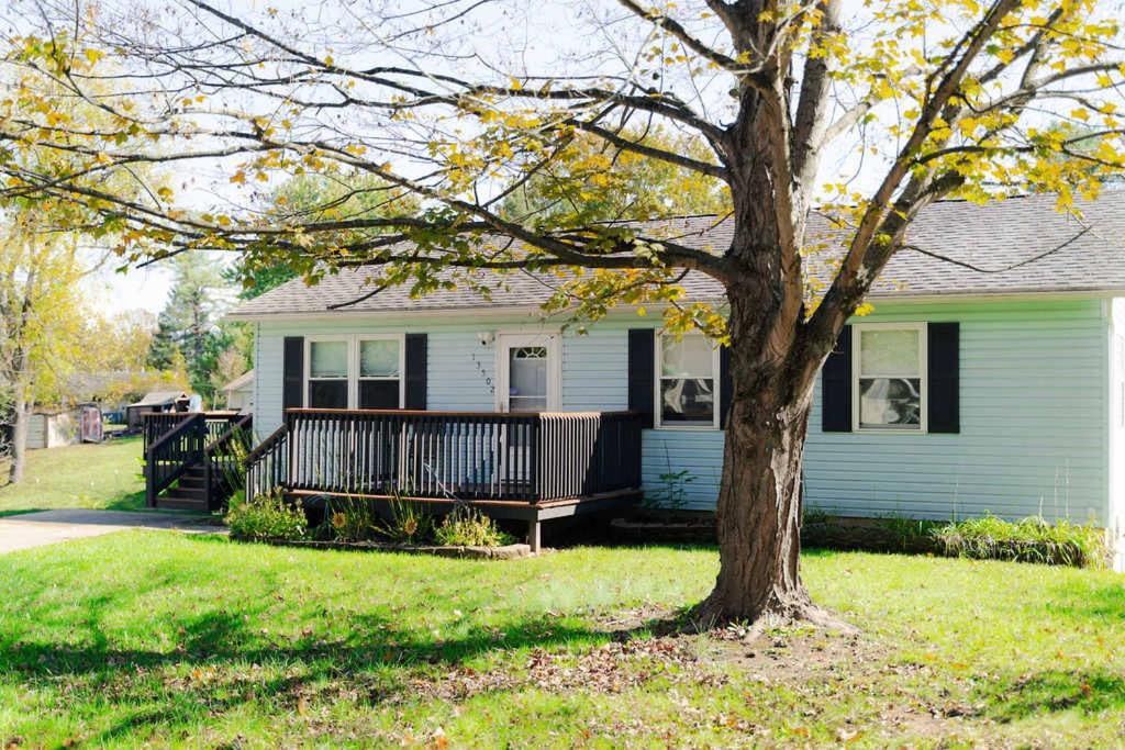 une maison avec un banc devant un arbre dans l'établissement Blue Heron Cottage with Game Room, Deck & Hot Tub, à Logan