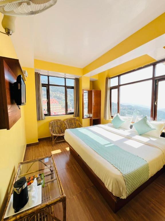 a bedroom with a large bed with yellow walls and windows at Harmony Sentiments in Shimla