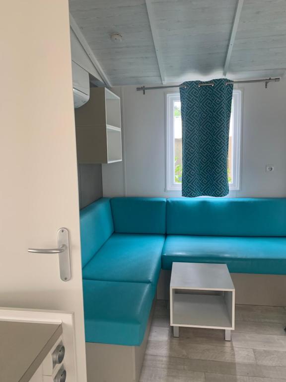 ein blaues Sofa in einem kleinen Zimmer mit Fenster in der Unterkunft Mobil home 6 pers camping 5 in Montalivet-les-Bains