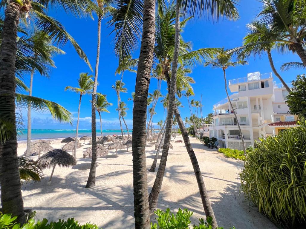 a view of a beach with palm trees and a building at Condo very close beach in Punta Cana