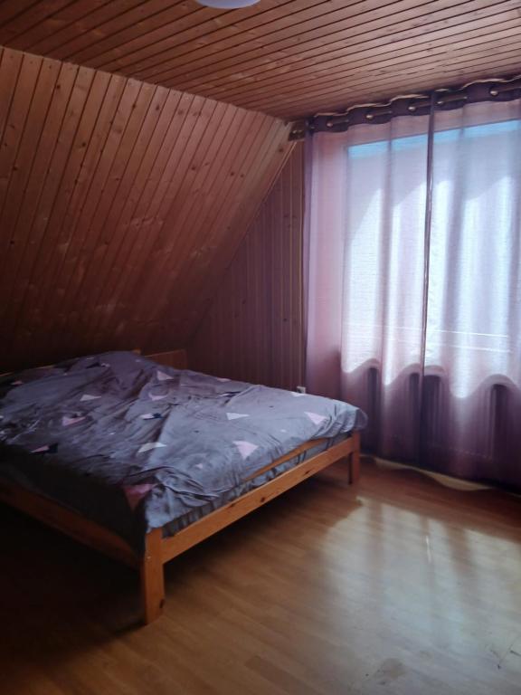 a bed in a wooden room with a window at Sauleskrasti 
