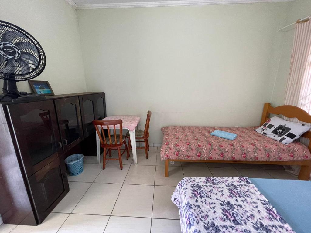 a bedroom with a bed and a table with a fan at Hostel e Pousada Vó Lili in Joinville