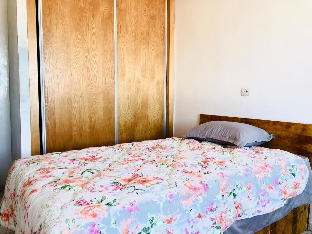 カサブランカにある卡萨布兰卡华人民宿の花柄の掛け布団と木製のヘッドボードを備えたベッド