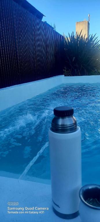 eine Wasserflasche auf einem Tisch neben einem Pool in der Unterkunft DUPLEX ATARDECERES in Chascomús