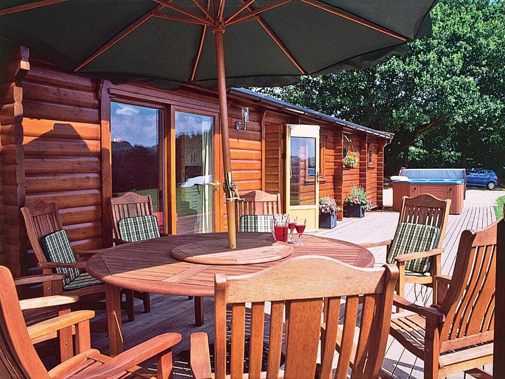 a wooden table and chairs with an umbrella on a deck at Cider Mill Lodge - Hw7420 in Tintern