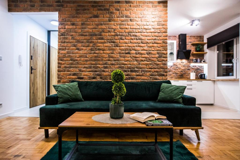 een woonkamer met een groene bank en een bakstenen muur bij Clara in Rzeszów