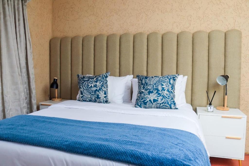 a bedroom with a large bed with blue and white pillows at The Rest in Maseru