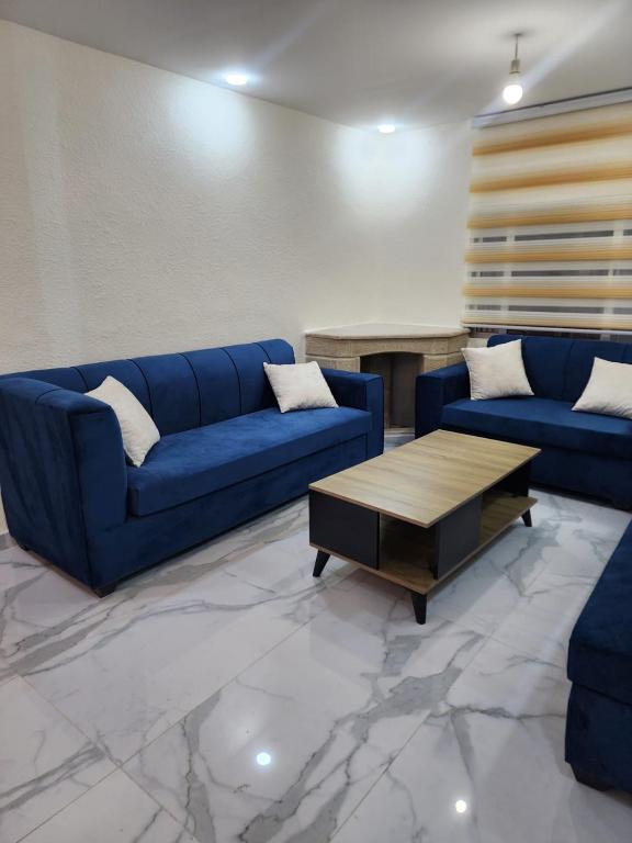a living room with blue couches and a coffee table at شقة مفروشة apartment amman alnuzzha in Amman